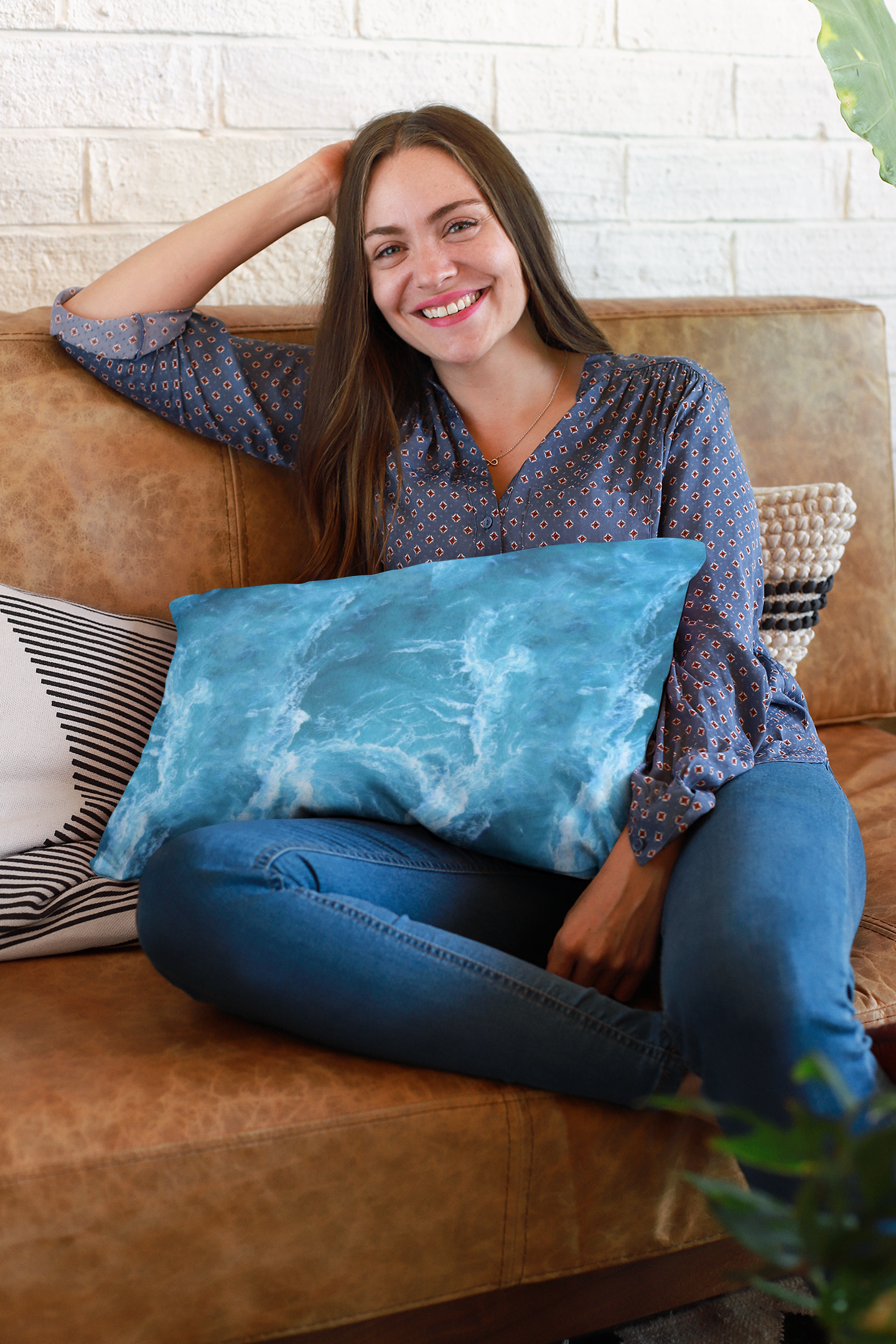 Woman seated on couch holding pillow covered in ocean themed pillow case